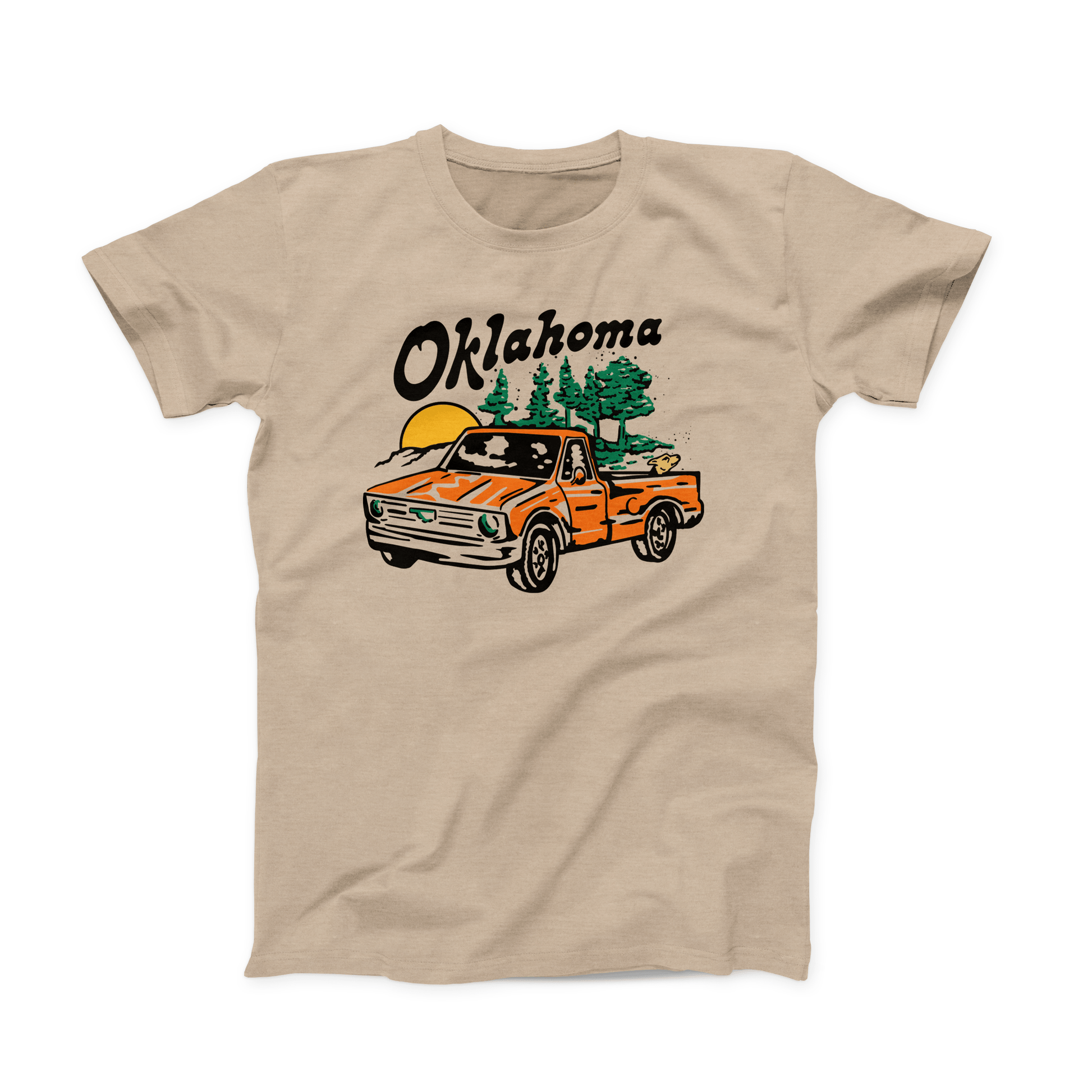 A Heather Tan Oklahoma t-shirt. The Design is of an orange, old-school truck with a dog in the bed of the truck. And in the background are green trees and a yellow setting sun. Above the design is "Oklahoma" in black, angled font.