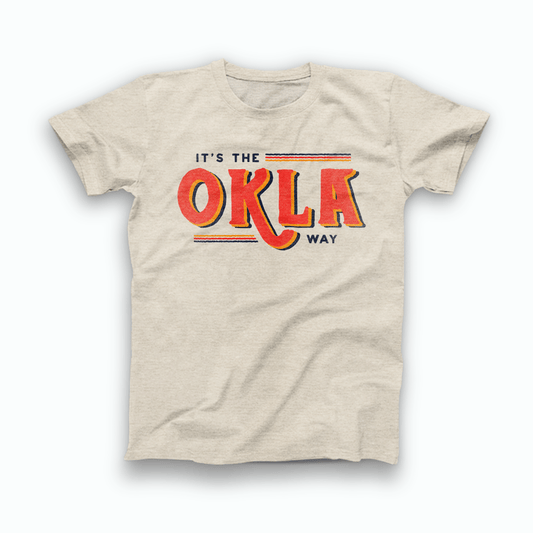 Natural Heather Prism colored Oklahoma T-shirt. Screen printed in a vintage style in orange, yellow, and navy. "IT'S THE OKLA WAY" is written across the shirt. In small navy font across the top is "It's the" with 3 lines of color stretched after it. In the middle is "OKLA." And, small across the bottom of the design is 3 stretched lines of color leading to "Way" in navy.