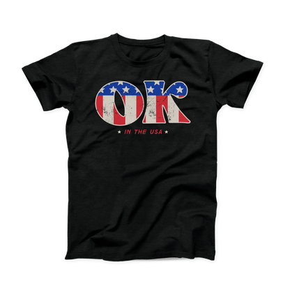 Solid black colored Oklahoma t-shirt. Screen printed in a vintage, distressed style is a large "OK" with the American flag print inside the letters.  And in smaller font below is "IN THE USA" in red with a small white star on either side. 