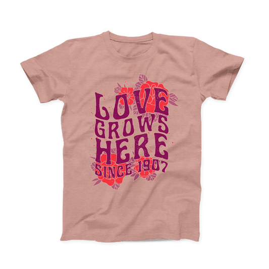 Heather Prism Peach colored Oklahoma T-shirt. Large design across the whole front of the shirt with red roses in the background of the top and bottom.  "LOVE GROWS HERE" in a stacked purple font with "Since 1907" below it. 