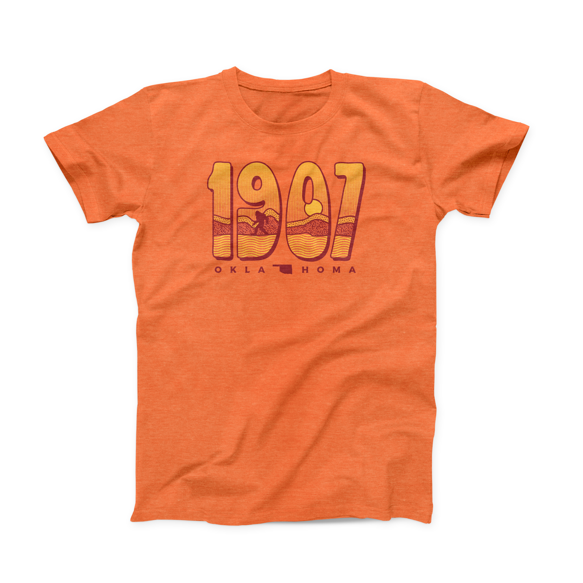 Heather Orange Oklahoma t-shirt. "1907" is the main design, with a sunset and a Sasquatch within the year. "OKLA" (state symbol) "HOMA" in small darker font below the year. 