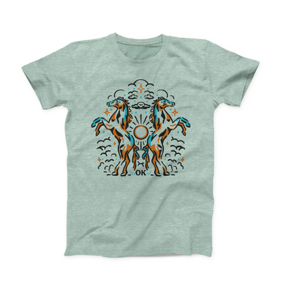 Heather Prism Dusty Blue colored Oklahoma t-shirt. Styled like a Rorschach Inkblot is depicted 2 horses, back to back, raised up on hind legs. There is a sun between them and clouds and stars around them. In small font in the center at the bottom is "OK." The whole design is done in turquoise, black and brown.
