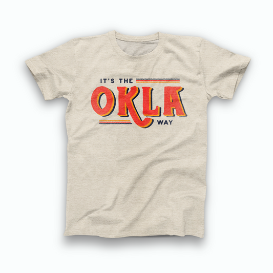 Natural Heather Prism colored Oklahoma T-shirt. Screen printed in a vintage style in orange, yellow, and navy. "IT'S THE OKLA WAY" is written across the shirt. In small navy font across the top is "It's the" with 3 lines of color stretched after it. In the middle is "OKLA." And, small across the bottom of the design is 3 stretched lines of color leading to "Way" in navy.