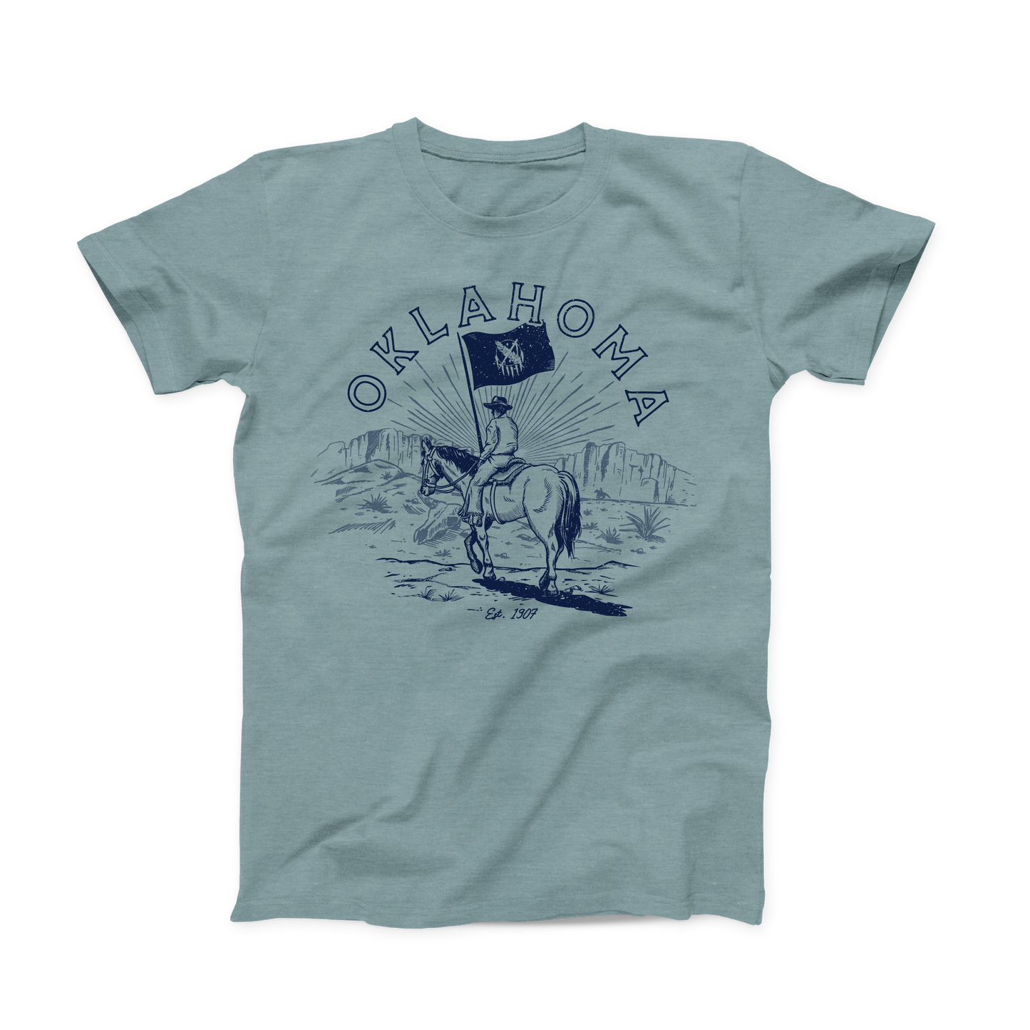 Heather Dusty Blue colored Oklahoma T-shirt. Screen printed in Navy is a Cowboy on horseback, traveling through a canyon with the Oklahoma State Flag. "Oklahoma" is written in a half circle above the design. And below the design in small font is "Est. 1907"